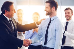 Two businessmen smiling while shaking hands